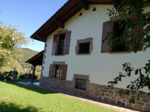 Casa blanca con ventanas marrones y patio en Casa Exkanda Etxea, en Sumbilla