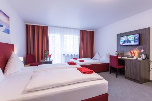 a large hotel room with two beds and a couch at Hotel Himalaya Frankfurt City Messe in Frankfurt/Main