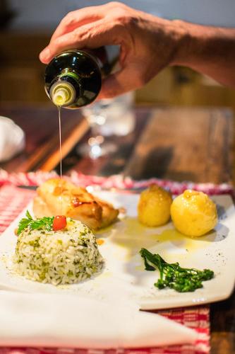 a person is pouring wine into a plate of food at Pousada Chão de Minas Ouro Preto in Ouro Preto