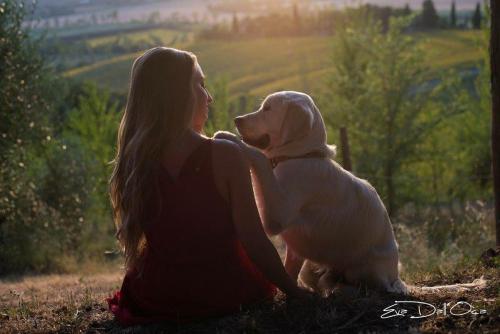 a woman sitting in the grass with a white dog at Agriturismo Pieve Sprenna in Buonconvento