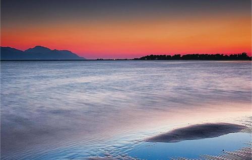 a sunset over the water with a rock in the sand at Apartmani Galić in Ploče