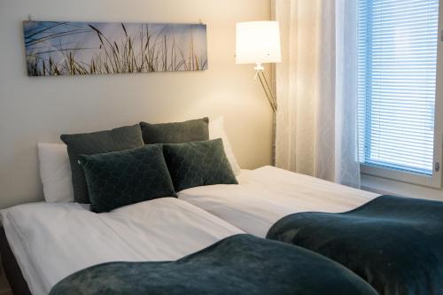 1 dormitorio con 1 cama con sábanas blancas y almohadas verdes en Antintorni Apartment 7, en Pori