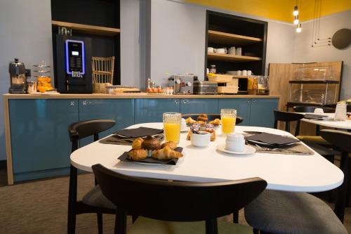 a table with a plate of food and orange juice at The Originals Boutique, Hôtel des Sources, Nevers Nord in Pougues-les-Eaux