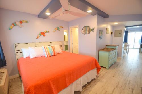 een slaapkamer met een bed met een oranje sprei bij Emerald Villa in Panama City Beach