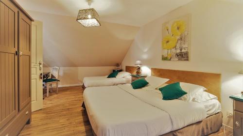 a bedroom with two beds with green and white pillows at Location de La Ferme De Kerraoul in Combrit