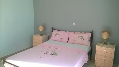 ナフプリオにあるAnastasia Apartmentのベッドルーム1室(ピンクのシーツが入ったベッド1台、ナイトスタンド2台付)