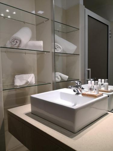 a bathroom with a sink and a mirror and towels at Travellers Pearl by Storytellers in Funchal