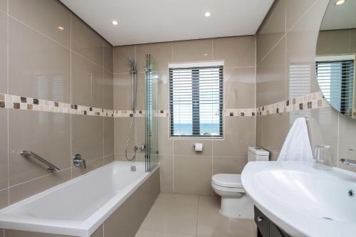 a bathroom with a tub and a toilet and a sink at Ocean Vista Boutique Guest House in Durban