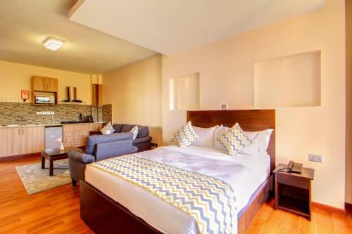 a bedroom with a bed and a chair and a kitchen at Highlands Suites Hotel Apartments in Nairobi