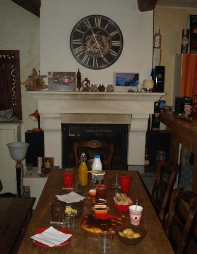 een eettafel met een grote klok aan de muur bij Au Bout De La Route in Prads-Haute-Bléone