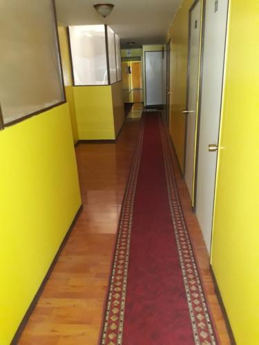 a long hallway with a red carpet and yellow walls at Hotel Aymara in Calama