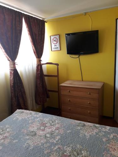 1 dormitorio con 1 cama, TV y vestidor en Hotel Aymara, en Calama