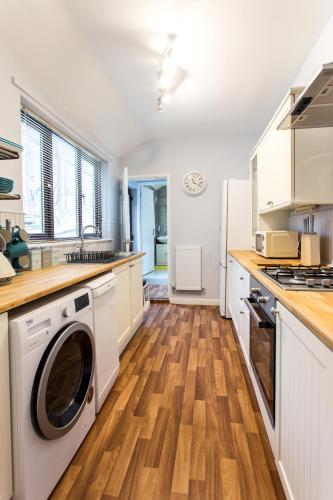 a kitchen with white cabinets and a washer and dryer at Northwood Park View in Stoke on Trent