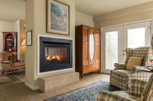 a living room with a fireplace and two chairs at The Yellow House on Plott Creek in Waynesville