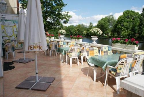 eine Terrasse mit einem Tisch, Stühlen und einem Sonnenschirm in der Unterkunft Hotel Kubrat an der Spree in Berlin