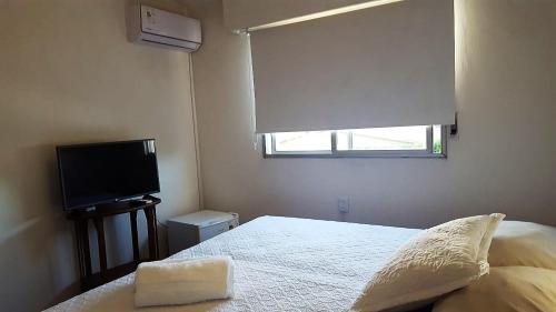 a bedroom with a bed with a window and a television at Bidieen Inn Uruguay in Carrasco