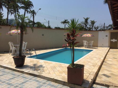 a swimming pool with two palm trees next to a house at casa com piscina a 100 mts a beira mar in Mongaguá