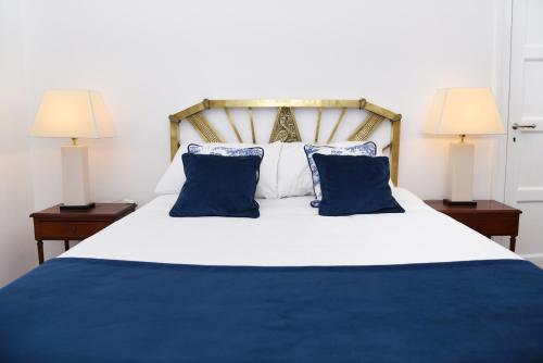 a bedroom with a bed with blue pillows and two lamps at Gran Texier Hotel Casino in Concepción del Uruguay