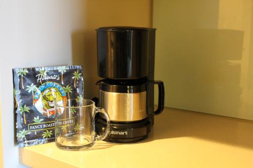 a coffee maker sitting on a counter next to a glass at LSI Resorts at Ala Moana in Honolulu