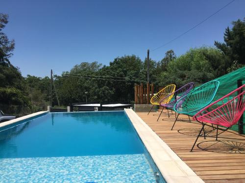 three chairs sitting on a deck next to a swimming pool at Terralagum in Villa Parque Siquiman