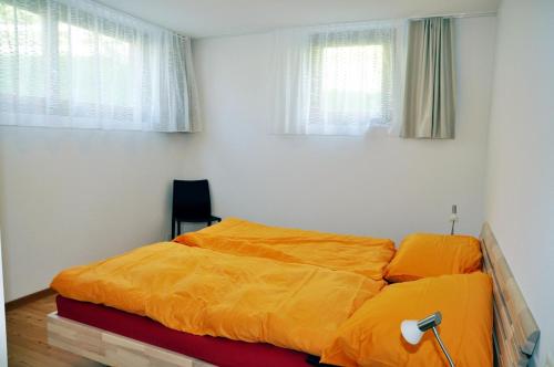 ein Bett mit einer orangefarbenen Bettdecke in einem Schlafzimmer in der Unterkunft Crastuoglia 720 - Nr. 1 in Scuol
