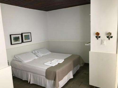 a white bedroom with a bed with two towels on it at Hotel Velho Monge in Teresina