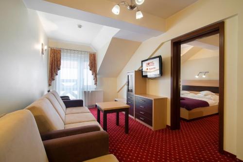 Habitación de hotel con sofá, cama y espejo en Hotel Continental, en Krynica Morska