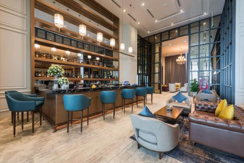 a lobby with a bar with blue chairs and a couch at FLC Grand Hotel Samson in Sầm Sơn