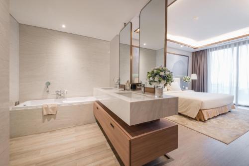 a bathroom with a sink and a tub and a bed at FLC Grand Hotel Samson in Sầm Sơn