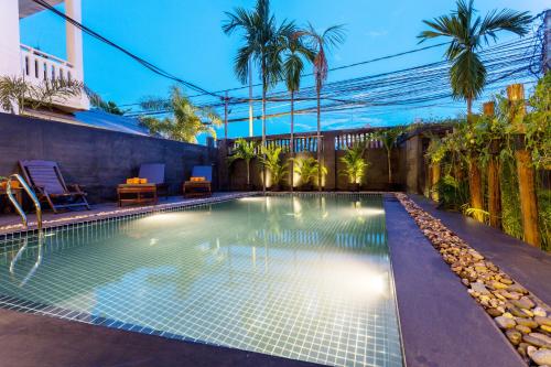 a swimming pool in a backyard with palm trees at Hima Boutique in Siem Reap