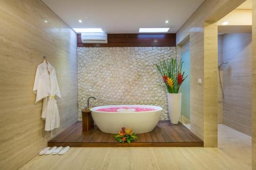 a bathroom with a bath tub and a vase with flowers at Entrada Seminyak Villa By Nagisa Bali in Seminyak