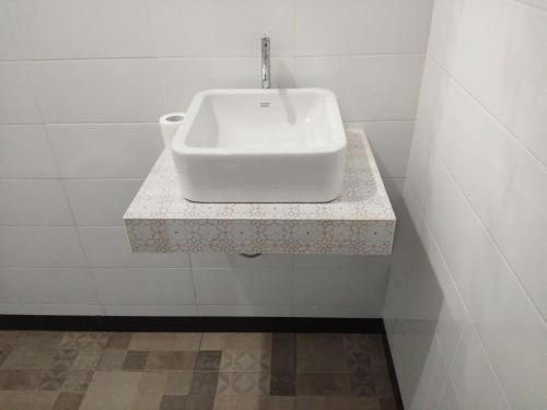 a white sink in a white tiled bathroom at Tirta Yoga Inn in Padangbai