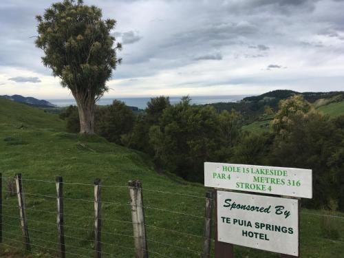 a sign on a fence in a field with a tree at Te Puia Hot Springs Hotel in Te Puia