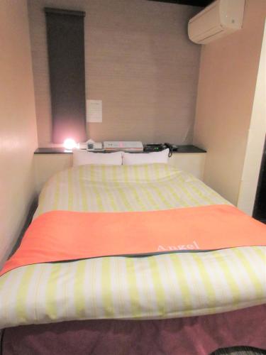 a bedroom with a bed with a striped blanket at Hotel Angel (Adult Only) in Yokohama