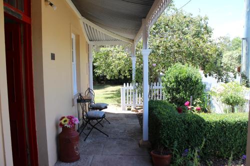 a porch of a house with a chair and flowers at Bellamona Cottage Longford in Longford