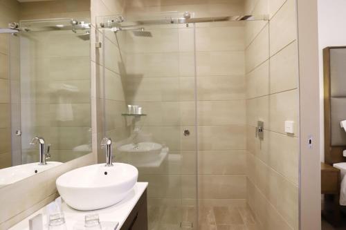 a bathroom with a sink, toilet, and shower stall at Clarendon Hotel Melbourne in Melbourne