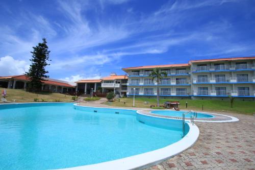 a large swimming pool in front of a hotel at Coral Palms in Amami