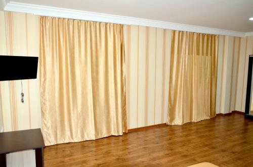 a living room with curtains and a wooden floor at KavKaz Hotel & Restaurant in Marneuli