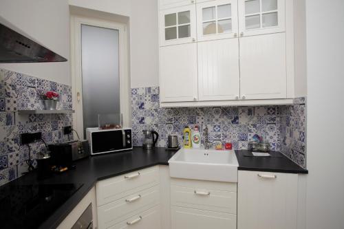 a kitchen with white cabinets and a sink at Luxury apartment Spálená in Prague
