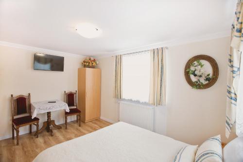 a bedroom with a bed and a table and a window at Pokoje Gościnne Gazda in Polanica-Zdrój