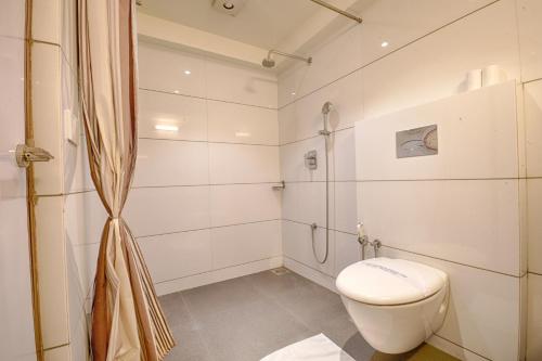 a white bathroom with a toilet and a shower at Hotel Platinum Residency in Ahmedabad