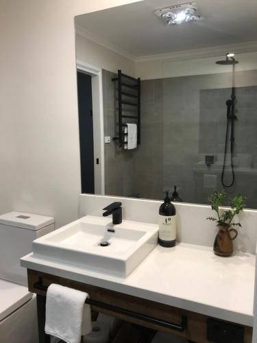 a white bathroom with a sink and a mirror at Holly House Bed & Breakfast in Moyhu