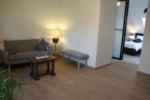 a living room with a couch and a table and a bed at Logies Tommenmolen in Grimbergen