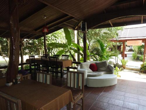 a patio with a white couch and a table and chairs at Buddha Raksa in Thong Nai Pan Yai