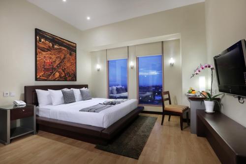 a bedroom with a large bed and a flat screen tv at Grand Candi Hotel in Semarang