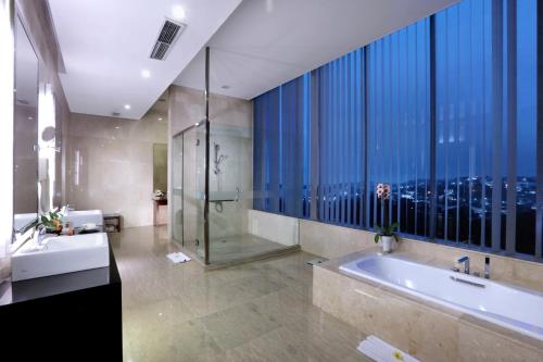 a bathroom with a tub and a shower and a window at Grand Candi Hotel in Semarang