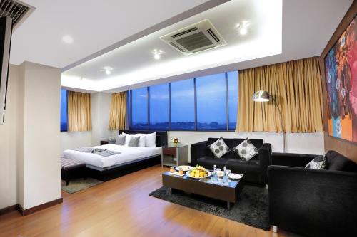 a living room with a couch and a bed at Grand Candi Hotel in Semarang