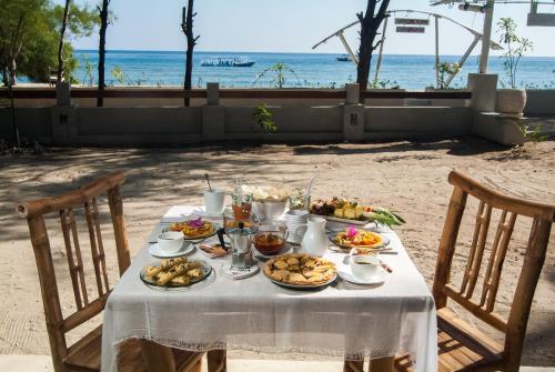 ein Tisch mit Essen drauf mit Strand im Hintergrund in der Unterkunft Coral Flora Villa Beach Front in Gili Trawangan