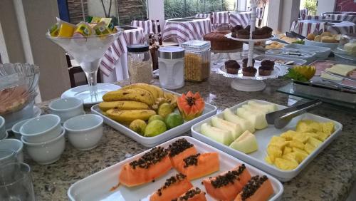 een tafel met dienbladen van verschillende soorten levensmiddelen bij Primavera Palace Hotel in Nova Andradina