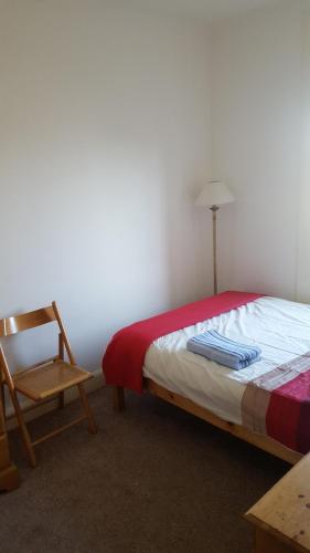 a bedroom with a bed and a chair and a lamp at Snug - Krayr Apartment in Helensburgh